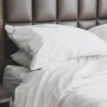 Close-up of an ivory sateen pillowcase against a padded headboard