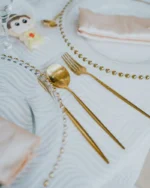 Aurelle gold fork, knife and spoon on beaded glass plates in an elegant table setting