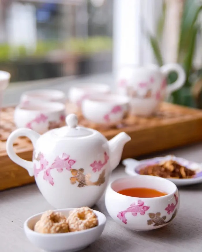 Camellia porcelain teapot and teacups with pink floral detail served with biscuits