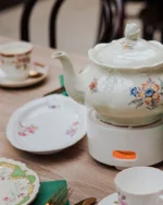 Camellia porcelain teapot on a warmer with matching cups and dessert plates