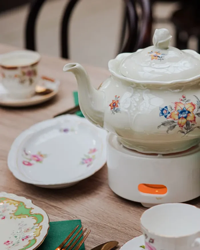 Camellia porcelain teapot on a warmer with matching cups and dessert plates