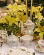 Camellia porcelain teapot and cups on a table decorated with yellow lilies