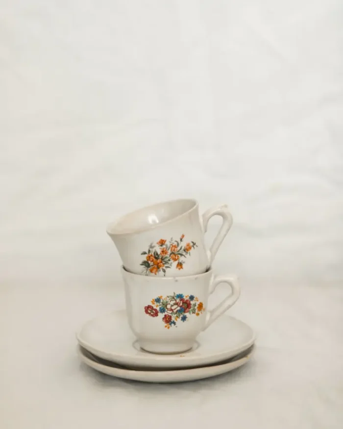 Two stacked Camellia porcelain teacups on saucers against a soft white background