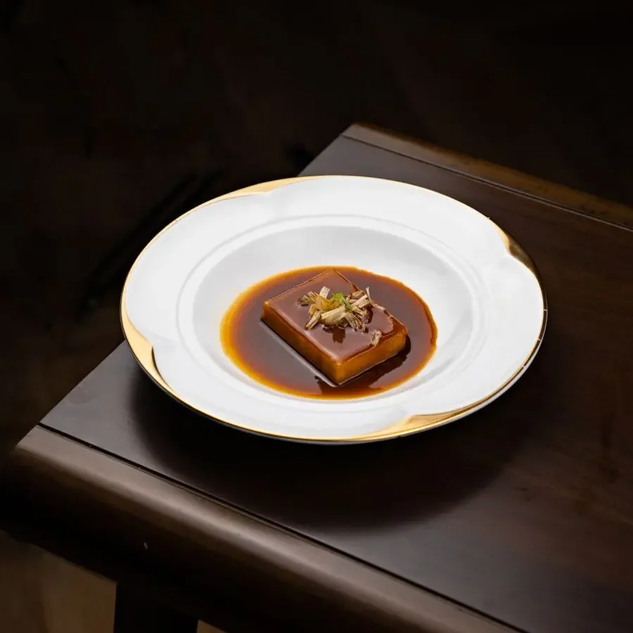 White porcelain plate with gold-trimmed rim serving a plated dessert on a dark wooden table