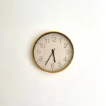 Halo minimal wall clock with a slim gold-tone rim and white dial on a clean white wall