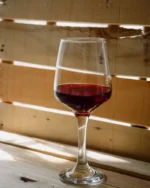 Lumière crystal wine glass with red wine on a rustic wooden surface in warm natural light