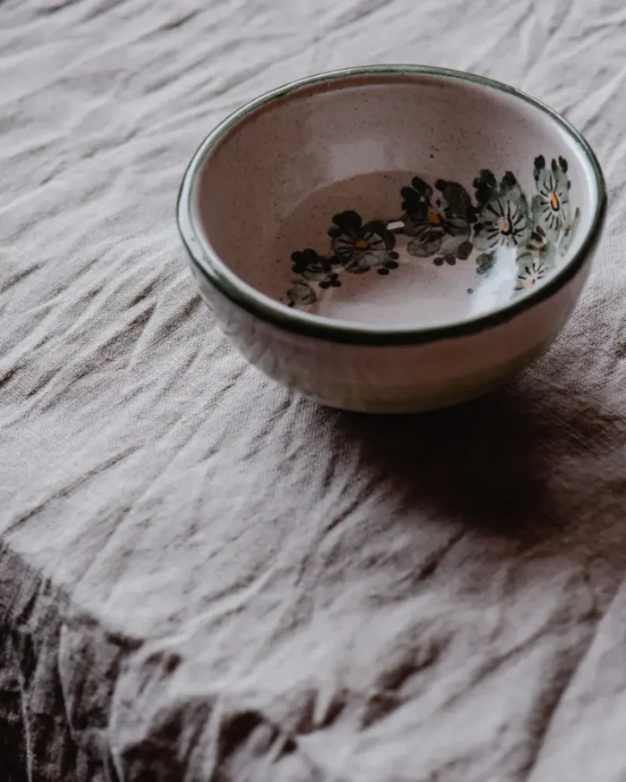 Terra stoneware bowl with a soft speckled glaze on crumpled grey linen