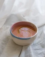 Terra stoneware bowl with a blue rim holding warm soup on white linen