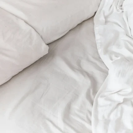 Soft drape and fold of white sateen bed linen
